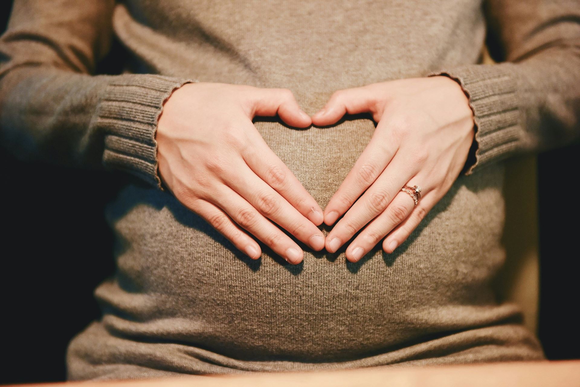 Hands in the shape of a heart over pregnant belly